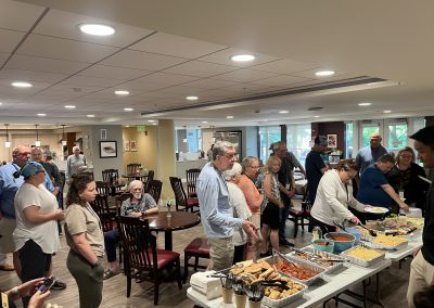Guests and caregivers at Hope Lodge Boston gather around a buffet-style table filled with a variety of dishes prepared by the PTP Gives Back and AWS MASS SMB teams, as they serve themselves dinner.