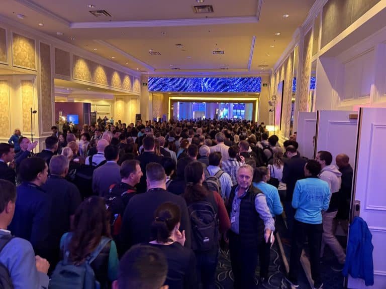 A large crowd of attendees at AWS re:Invent 2024 in a hallway leading to event sessions.
