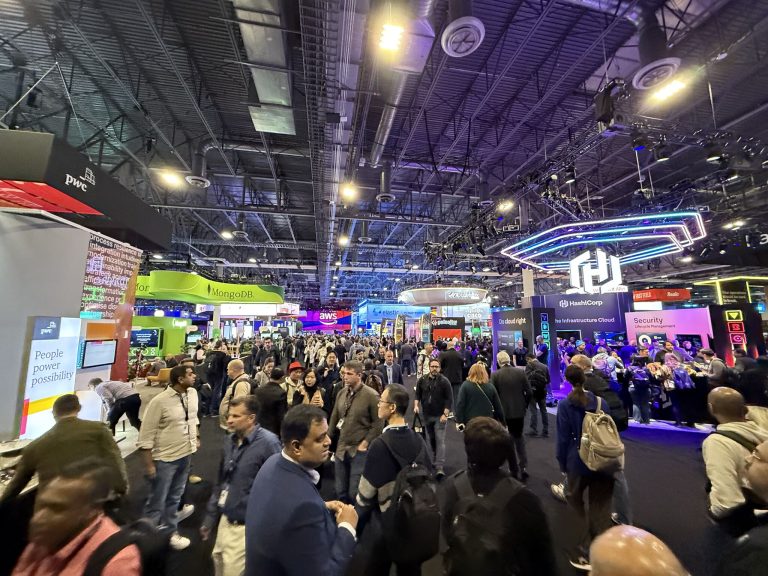 The bustling expo floor at AWS re:Invent 2024, featuring booths from MongoDB, HashiCorp, and PwC, with attendees engaging in discussions.