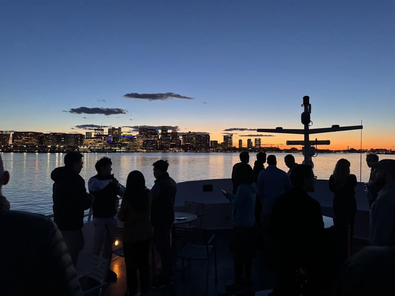 Attendees networking on the top deck of the Seaport Elite yacht during sunset at the Bio-IT Harbor Cruise Networking Event.
